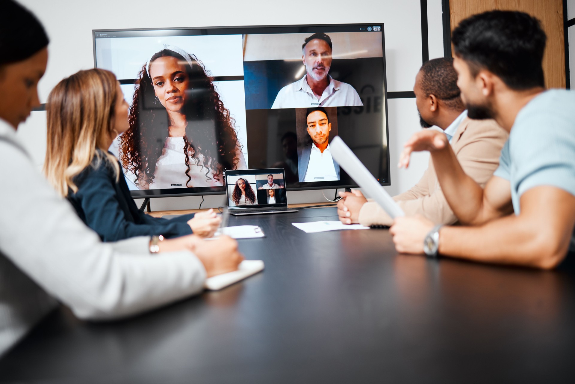 Cropped shot of a diverse group of businesspeople sitting in the boardroom during a meeting with their international colleagues via video chat